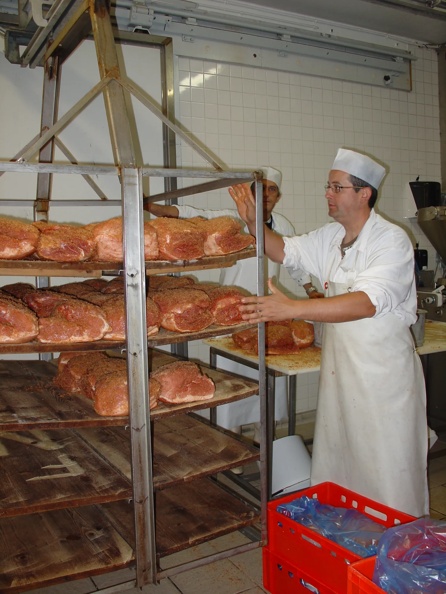 Nicolas en train de saler les noix de jambon au sel sec sur des planche d'épicéas