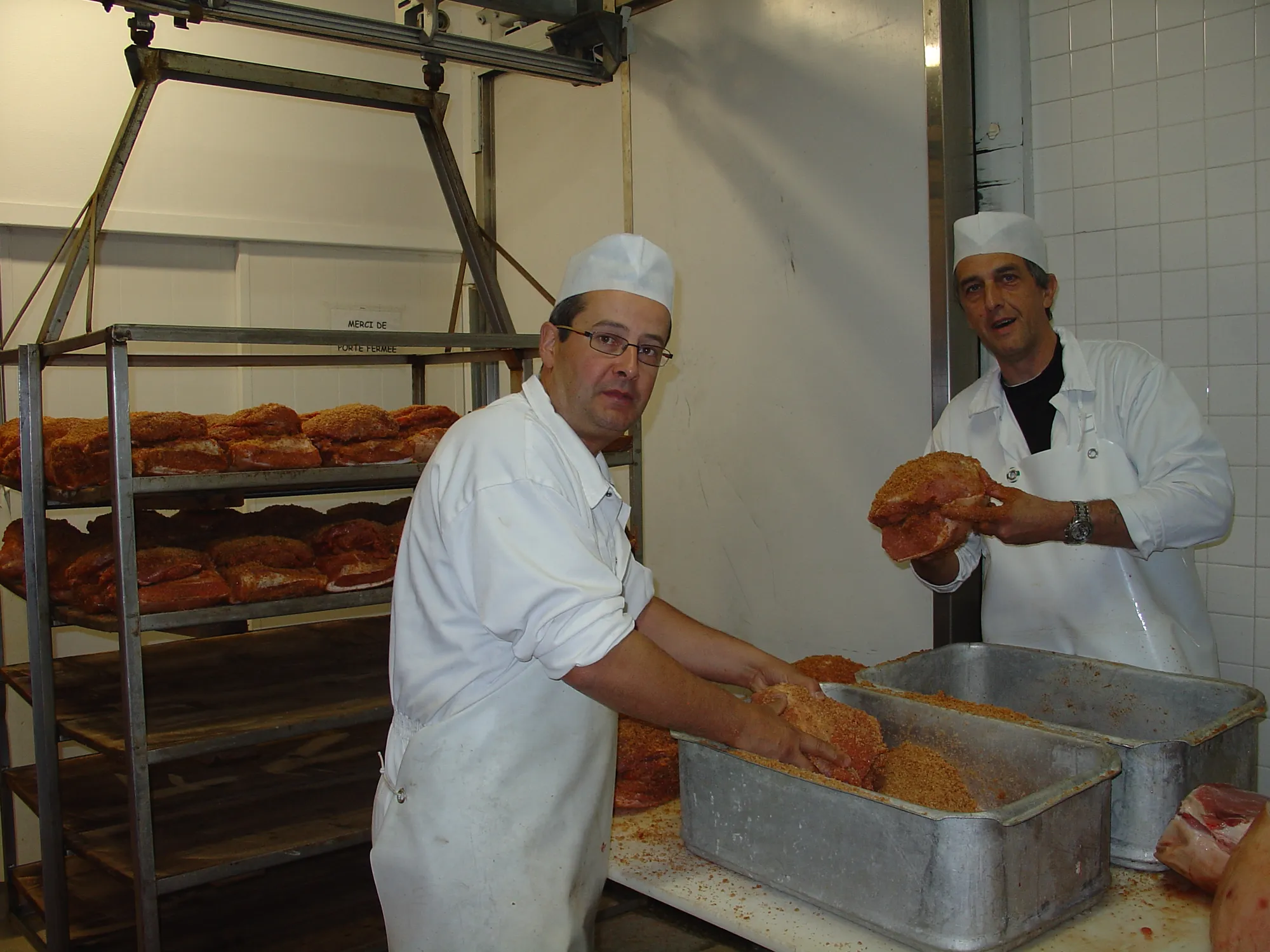Nicolas et Laurent en train de saler les noix de jambon au sel sec sur des planche d'épicéas